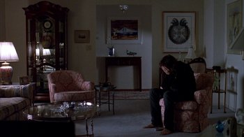 Movie still from “Paranoid Park” (2007), directed by Gus Van Sant – A man sitting on a chair in a living room; Wide shot, High angle