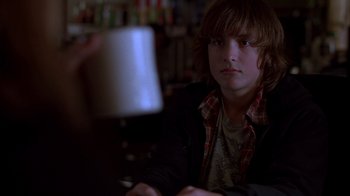 Movie still from “Paranoid Park” (2007), directed by Gus Van Sant – A young man sitting at a table in a room; Close Up shot, Over the shoulder angle
