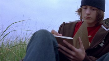 Movie still from “Paranoid Park” (2007), directed by Gus Van Sant – A person sitting in a chair reading a book; Close Up shot, Low angle
