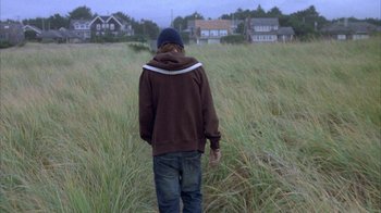 Movie still from “Paranoid Park” (2007), directed by Gus Van Sant – A person walking through tall grass in a field; Wide shot, Over the shoulder angle