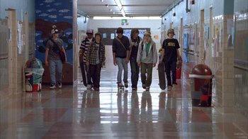 Movie still from “Paranoid Park” (2007), directed by Gus Van Sant – A group of young people walking down a hall way with skateboards; Wide shot, Low angle