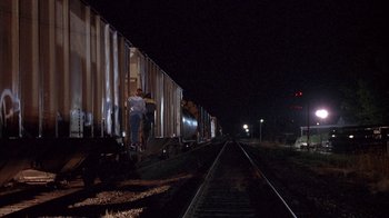 Movie still from “Paranoid Park” (2007), directed by Gus Van Sant – A man standing next to a train on a train track at night; Extreme Wide shot, Low angle