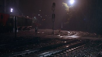 Movie still from “Paranoid Park” (2007), directed by Gus Van Sant – A person running on train tracks at night time; Extreme Wide shot, High angle