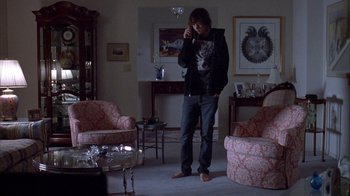Movie still from “Paranoid Park” (2007), directed by Gus Van Sant – A man standing in a living room talking on a cell phone; Wide shot, Low angle