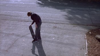 Movie still from “Paranoid Park” (2007), directed by Gus Van Sant – A person on a skate board on the street; Wide shot, High angle