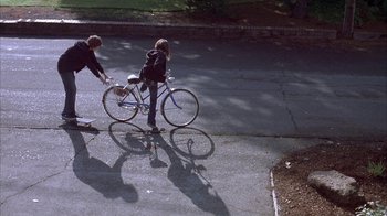 Movie still from “Paranoid Park” (2007), directed by Gus Van Sant – Two young people on a street with a bicycle; Wide shot, High angle