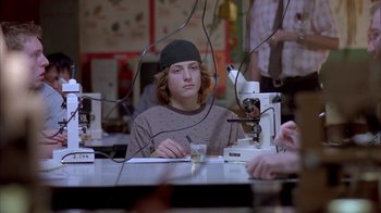 Movie still from “Paranoid Park” (2007), directed by Gus Van Sant – A man sitting in front of a microscope in a lab; Medium shot, Over the shoulder angle