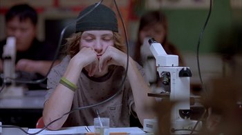Movie still from “Paranoid Park” (2007), directed by Gus Van Sant – A young man sitting in front of a microscope in a classroom; Medium shot, Low angle