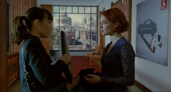 Movie still from “Passion” (2012), directed by Brian De Palma – Two women in front of a large window with a city view; Medium shot, Over the shoulder angle