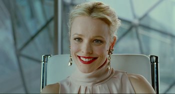 Movie still from “Passion” (2012), directed by Brian De Palma – A person wearing a dress smiling; Close Up shot, Over the shoulder angle