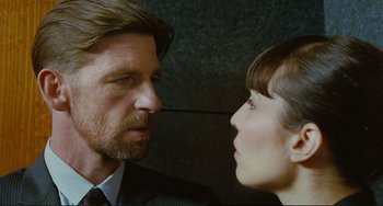Movie still from “Passion” (2012), directed by Brian De Palma – A man and a woman face to face in front of a brick wall; Close Up shot, Over the shoulder angle