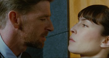 Movie still from “Passion” (2012), directed by Brian De Palma – A man and a woman face to face in front of a yellow wall; Close Up shot, Low angle