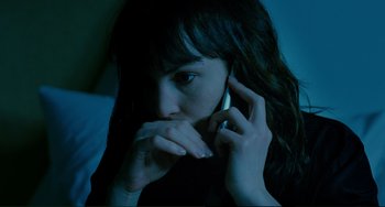 Movie still from “Passion” (2012), directed by Brian De Palma – A young woman holding a cell phone up to her face; Close Up shot, High angle