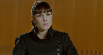 Movie still from “Passion” (2012), directed by Brian De Palma – A woman in a black jacket is looking at the camera; Close Up shot, Over the shoulder angle