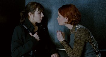 Movie still from “Passion” (2012), directed by Brian De Palma – Two women talking to each other in a room; Medium shot, Overhead angle