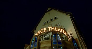 Movie still from “Passion” (2012), directed by Brian De Palma – A dance theater sign is lit up at night; Extreme Wide shot, Low angle
