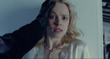 Movie still from “Passion” (2012), directed by Brian De Palma – A woman in a white robe holding her hand up to her head; Close Up shot, Over the shoulder angle