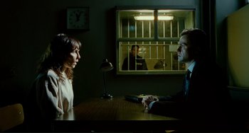 Movie still from “Passion” (2012), directed by Brian De Palma – A man and a woman sitting in front of a window; Medium shot, Over the shoulder angle