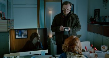 Movie still from “Passion” (2012), directed by Brian De Palma – A man standing in front of a computer screen; Medium shot, Over the shoulder angle