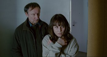 Movie still from “Passion” (2012), directed by Brian De Palma – A man and a woman standing next to each other in a room; Medium shot, Over the shoulder angle