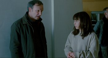 Movie still from “Passion” (2012), directed by Brian De Palma – A man and a woman standing next to each other in a room; Medium shot, Over the shoulder angle