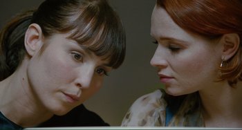 Movie still from “Passion” (2012), directed by Brian De Palma – Two women looking at one another with a serious look on their face; Close Up shot, Over the shoulder angle