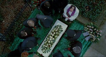Movie still from “Passion” (2012), directed by Brian De Palma – A group of people standing around a casket; Wide shot, Overhead angle