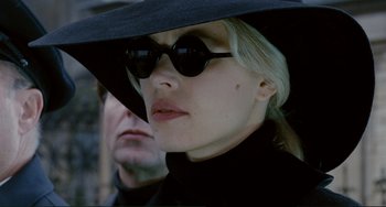 Movie still from “Passion” (2012), directed by Brian De Palma – A woman wearing sunglasses and a black hat; Close Up shot, Low angle