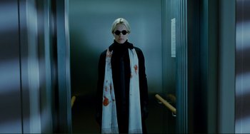 Movie still from “Passion” (2012), directed by Brian De Palma – A woman wearing sunglasses and a scarf in a elevator; Medium shot, Low angle