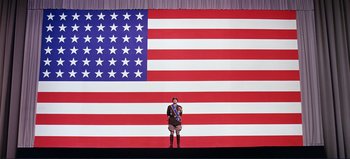 Movie still from “Patton” (1970), directed by Franklin J. Schaffner – A person standing in front of an american flag; Extreme Wide shot, Low angle