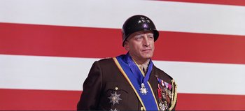 Movie still from “Patton” (1970), directed by Franklin J. Schaffner – A man in a military uniform wearing medals and a hat; Medium shot, Low angle