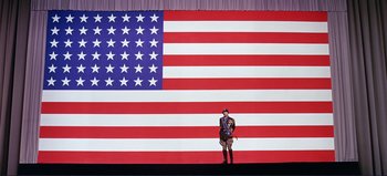 Movie still from “Patton” (1970), directed by Franklin J. Schaffner – A man in uniform standing in front of an american flag; Extreme Wide shot, Low angle