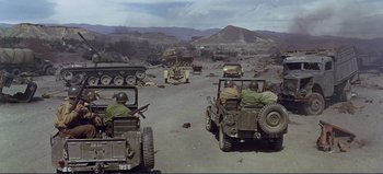 Movie still from “Patton” (1970), directed by Franklin J. Schaffner – A group of military vehicles driving down a dirt road; Extreme Wide shot, High angle
