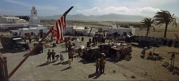 Movie still from “Patton” (1970), directed by Franklin J. Schaffner – A group of people standing around a building; Extreme Wide shot, High angle