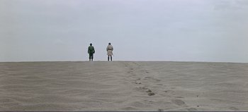 Movie still from “Patton” (1970), directed by Franklin J. Schaffner – Two people standing on the beach looking out at the ocean; Extreme Wide shot, High angle