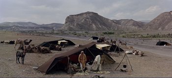 Movie still from “Patton” (1970), directed by Franklin J. Schaffner – A group of people standing next to tents in the desert; Extreme Wide shot, High angle