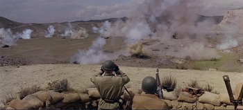 Movie still from “Patton” (1970), directed by Franklin J. Schaffner – A group of men standing on top of a dirt field; Wide shot, High angle