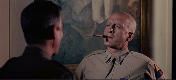 Movie still from “Patton” (1970), directed by Franklin J. Schaffner – A man smoking a cigar while talking to another man; Medium shot, Low angle