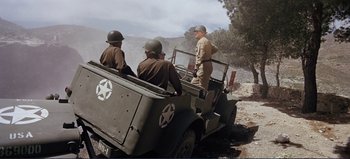 Movie still from “Patton” (1970), directed by Franklin J. Schaffner – A group of men riding on the back of an army vehicle; Wide shot, High angle