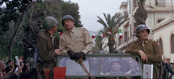 Movie still from “Patton” (1970), directed by Franklin J. Schaffner – Two men in military uniforms are standing next to a car; Medium shot, Over the shoulder angle