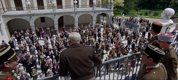 Movie still from “Patton” (1970), directed by Franklin J. Schaffner – An older man standing on a balcony looking at a crowd of people; Extreme Wide shot, High angle