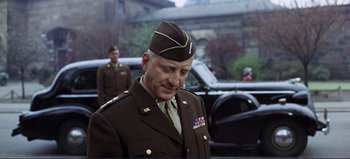 Movie still from “Patton” (1970), directed by Franklin J. Schaffner – A man in a military uniform standing in front of a building; Medium shot, Low angle