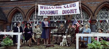 Movie still from “Patton” (1970), directed by Franklin J. Schaffner – A woman is speaking at a doughnut event; Wide shot, Low angle