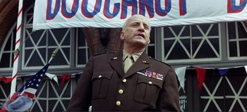 Movie still from “Patton” (1970), directed by Franklin J. Schaffner – A man in a military uniform standing in front of a banner; Medium shot, Low angle