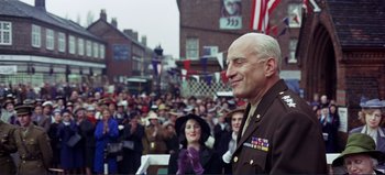 Movie still from “Patton” (1970), directed by Franklin J. Schaffner – An older man in a military uniform standing in front of a crowd of onlookers; Medium shot, Low angle