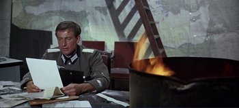 Movie still from “Patton” (1970), directed by Franklin J. Schaffner – A man sitting at a table in front of an open fire; Medium shot, High angle