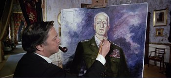Movie still from “Patton” (1970), directed by Franklin J. Schaffner – A man in a suit and tie holding a painting of an army officer; Medium shot, Low angle