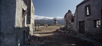 Movie still from “Patton” (1970), directed by Franklin J. Schaffner – An old building that has been demolished with a windmill in the background; Extreme Wide shot, Low angle