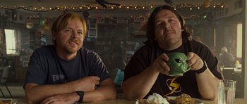 Movie still from “Paul” (2011), directed by Greg Mottola – Two men sitting at a table with a cup of coffee; Medium shot, Low angle
