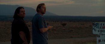 Movie still from “Paul” (2011), directed by Greg Mottola – A man standing on a dirt field at night; Medium shot, Over the shoulder angle
